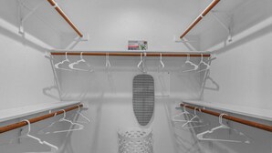 A walk-in closet with wooden rods, a hanging iron, and a white laundry basket. - Stylish Retreat - Close to Downtown - Open Layout (Austin)