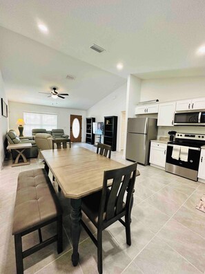 A modern kitchen with white cabinets, a stainless steel refrigerator, and a black oven.