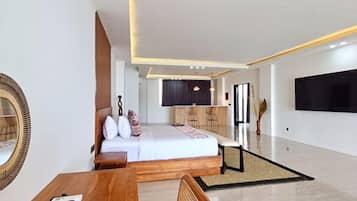 A modern hotel room with a bed, a wooden table, a TV, and a seating area.