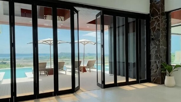 A modern interior with a sliding glass door leading to an outdoor area with a pool and chairs. - Villa Teraum (Pujut)