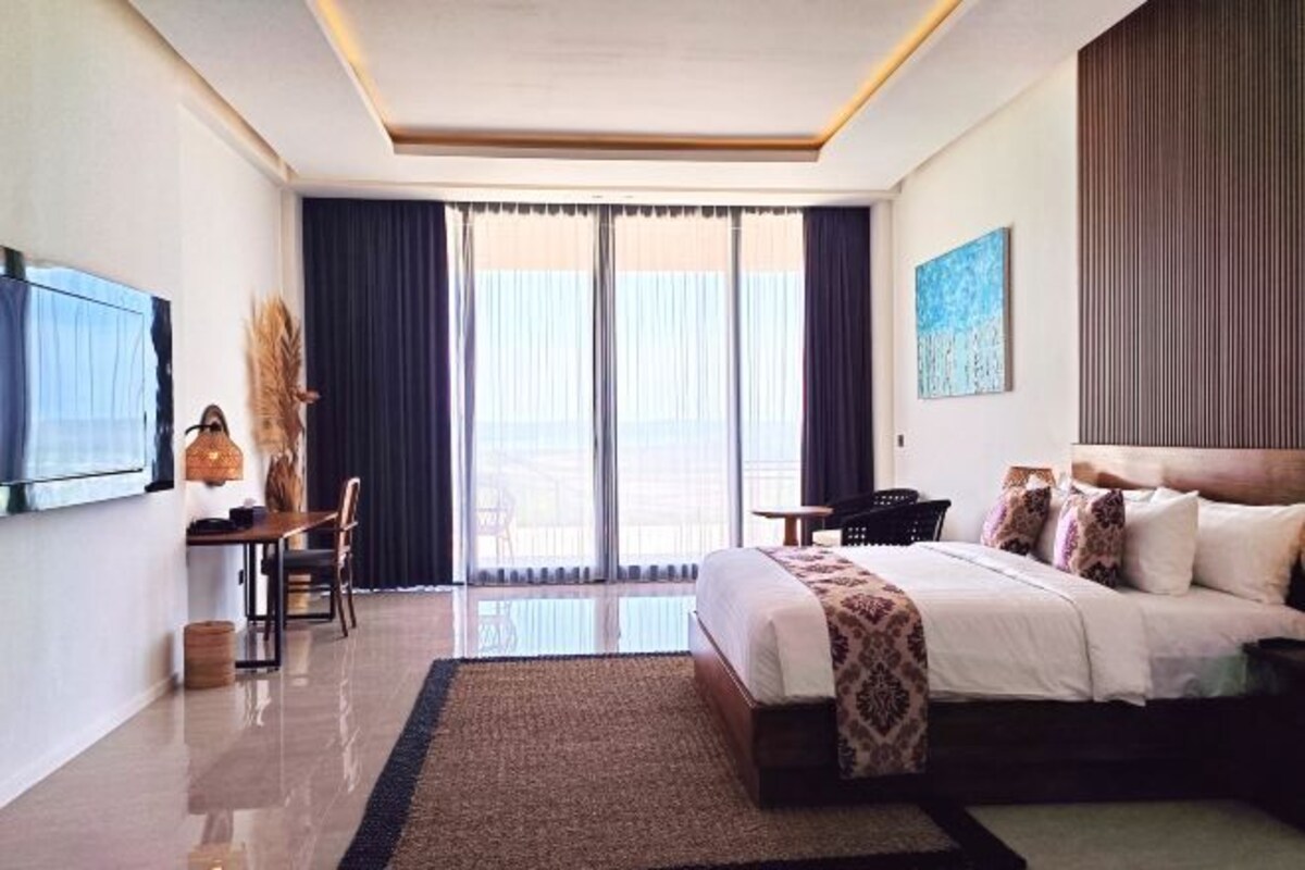 Ein Hotelzimmer mit Bett, Schreibtisch, Stuhl, Fernseher und Blick ins Freie.