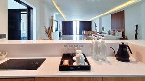 A modern hotel room with a kitchen area, a dining table, and a bed with a headboard. - Villa Teraum (Pujut)