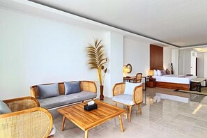 A hotel room with a sofa, chairs, a coffee table, a bed, and a bedside table with a lamp. - Villa Teraum (Pujut)