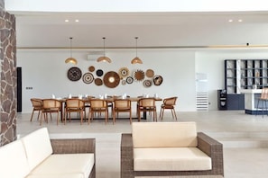 A modern living room with a dining area, featuring wicker furniture, pendant lighting, and decorative wall art. - Villa Teraum (Pujut)