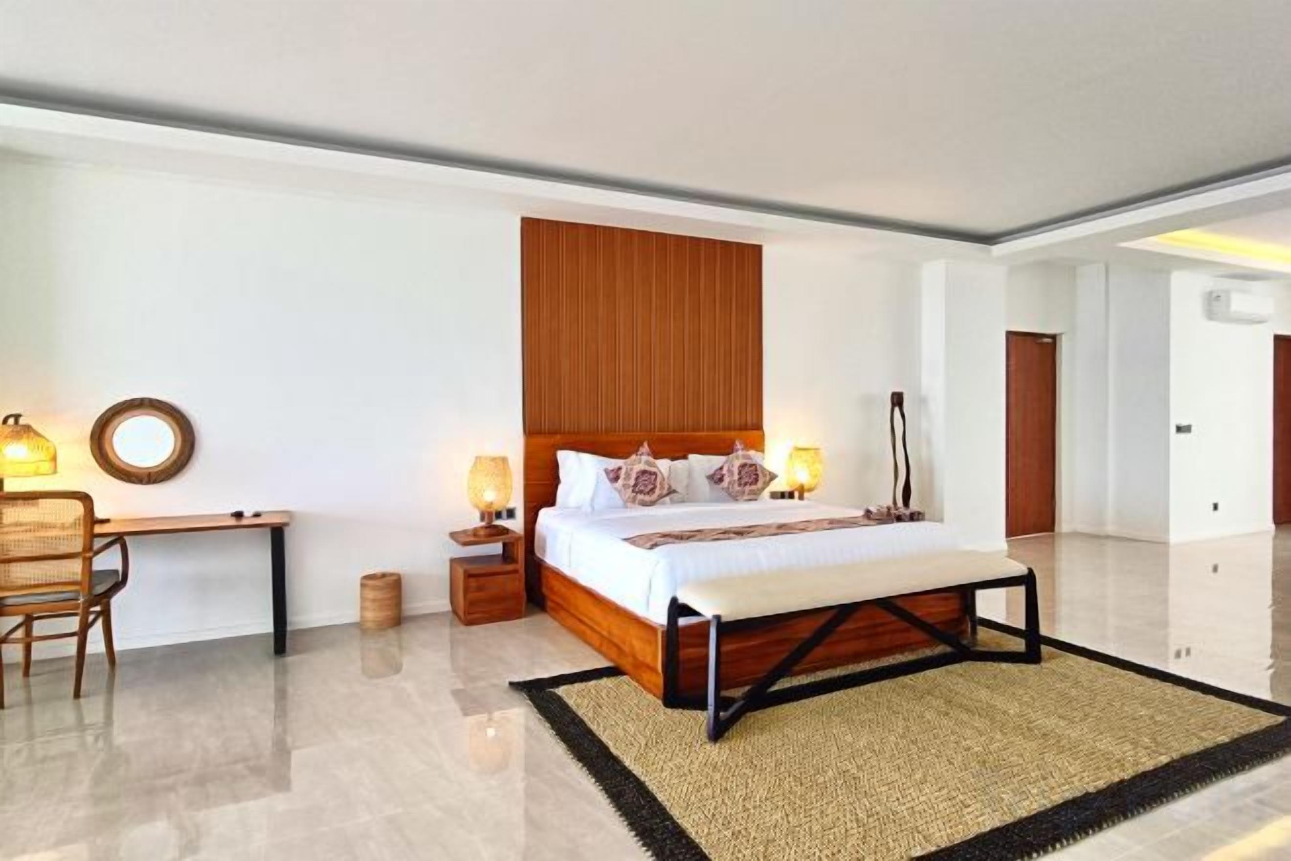 A modern hotel room with a large bed, bedside lamps, a desk, and a chair.