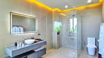A modern bathroom with a glass shower enclosure, a large mirror, and a built-in vanity with a sink.