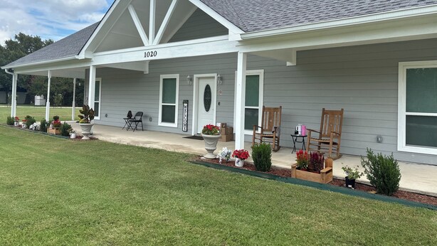 A house with a covered porch, a welcome sign, and a number 1020 on the front.