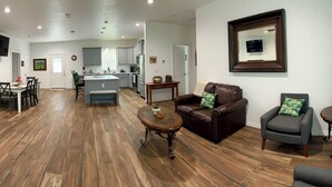 A spacious living room with a dining area, kitchen, and a TV mounted on the wall.