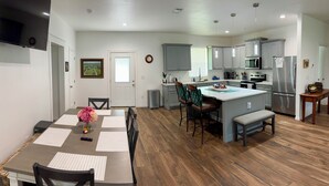A modern kitchen with grey cabinets, a central island, and stainless steel appliances.