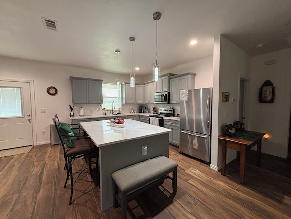 A modern kitchen with grey cabinets, stainless steel appliances, and a central island with seating.