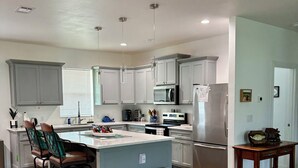 A modern kitchen with grey cabinets, a central island, and a wooden floor.