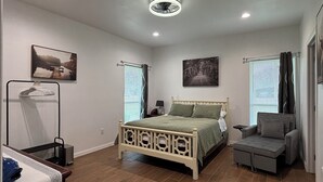 A bedroom with a bed, a chair, a wardrobe, and artwork on the walls.