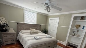 A bedroom with a bed, nightstand, dresser, and a ceiling fan.