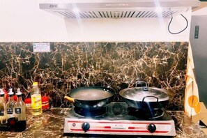 A kitchen with a gas stove, two pots, and bottles of cooking oil on a marble countertop. - Venn Hostel (Vientiane)