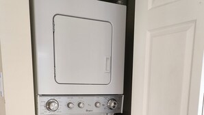 A compact laundry room with a stacked washer and dryer. - Quiet & Private Greek-Inspired Coach House in Ladner (Delta)