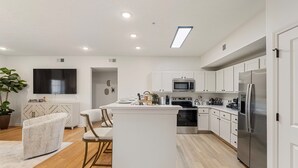 A modern kitchen with white cabinetry, stainless steel appliances, and a central island. - Walk to Davis Wade Stadium, Pet Friendly, King Bed (Starkville)