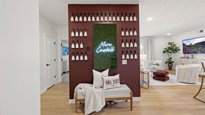 A modern living room with a bed, a neon sign, and a wall decorated with multiple light fixtures. - Walk to Davis Wade Stadium, Pet Friendly, King Bed (Starkville)