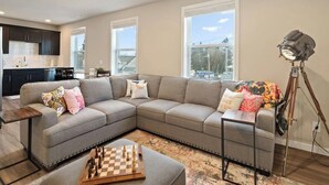 A modern living room with a sectional sofa, a chessboard, and a floor lamp.