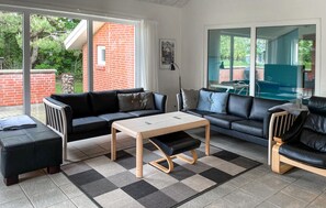 A modern living room with a black leather sofa, a wooden coffee table, and a black leather armchair. - Ocean front home in Spøttrup with sauna (Spøttrup)