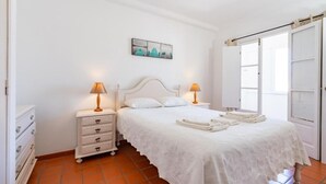 Une chambre à coucher avec un lit, des tables de chevet, une commode et une porte.