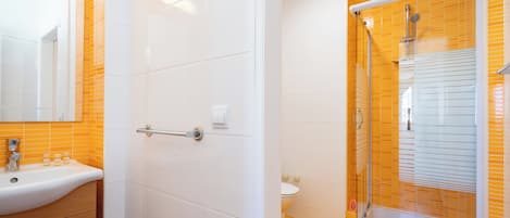 A bathroom with a white sink, a toilet, and a glass-enclosed shower.