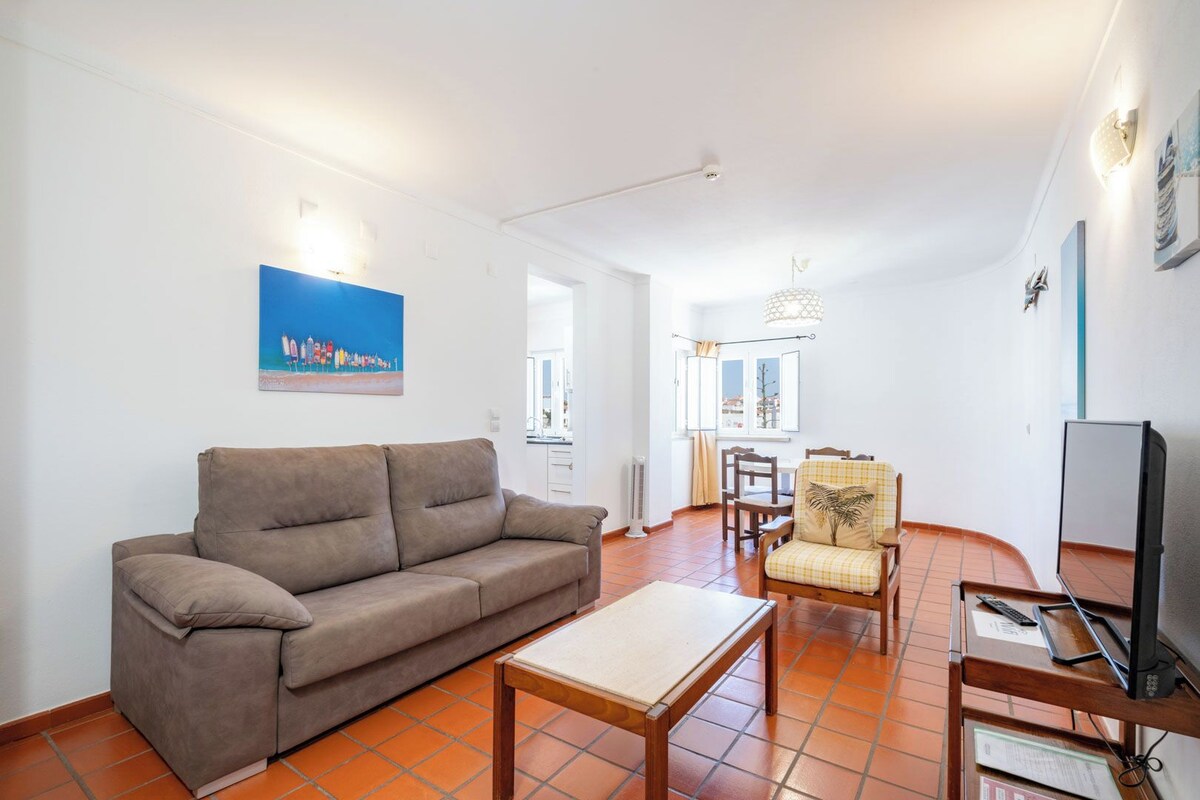 Een woonkamer met een bank, een tafel, een stoel en een televisie.