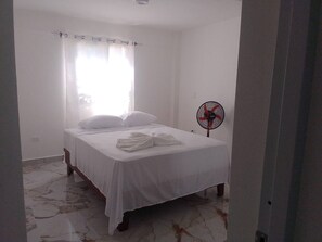 A bedroom with a bed, white curtains, a standing fan, and a marble floor. - The Perfect Place in Samana (Samaná)