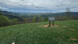 A sign indicating 'Grandview Overlook' with an elevation of 3240 feet, surrounded by lush green hills and a cloudy sky.