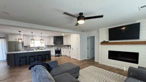 A modern kitchen with white cabinets, a central island, and a dining area with bar stools.