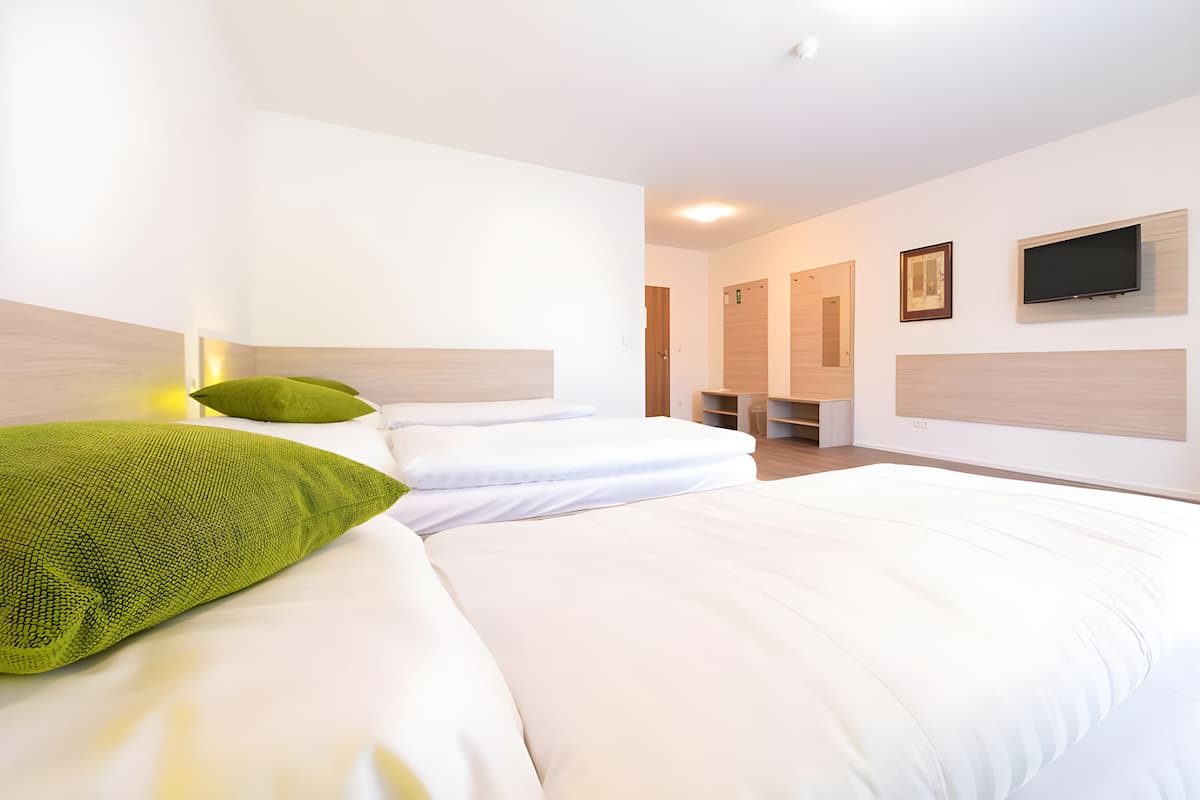 A hotel room with two beds, a TV mounted on the wall, and a small seating area.