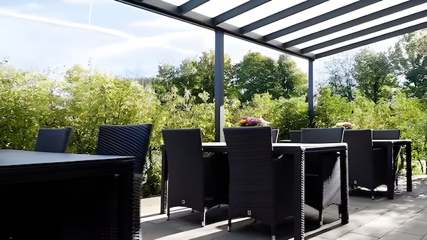 Un espace extérieur aménagé en terrasse, avec des meubles en osier noir et une structure en forme de pergola.
