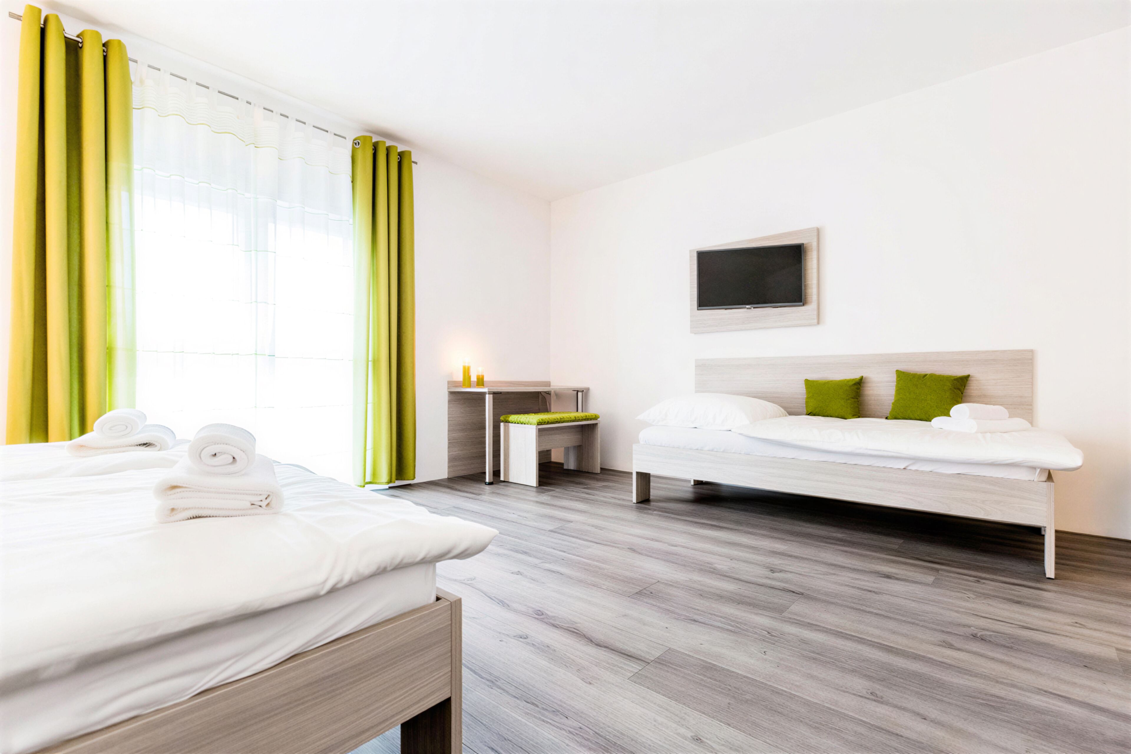Hotellihuone, jossa on sänky, työpöytä ja televisio.