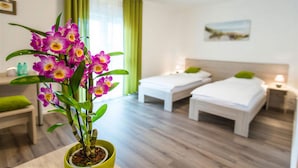 Une chambre d’hôtel avec deux lits, une plante verte et un tableau au mur.