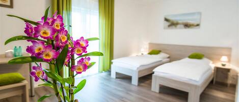 Una habitación de hotel con dos camas, una planta verde y un cuadro en la pared.