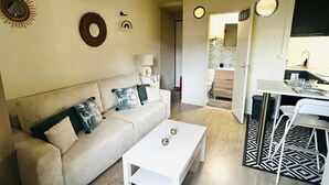 Ein gemütlicher Wohnbereich mit Sofa, Couchtisch, Esstisch und Küchenzeile.