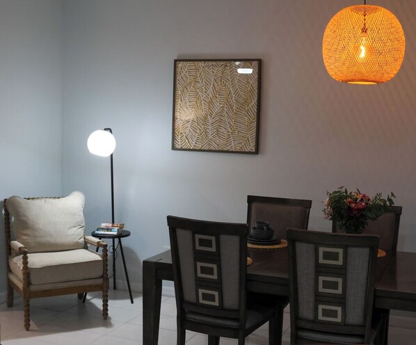 A dining area with a table, chairs, a floor lamp, and a wall-mounted light fixture.