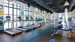 Un gimnasio con cintas de correr, máquinas de pesas y un banco azul.