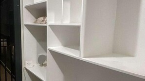 Une étagère blanche à plusieurs niveaux, dotée de différents compartiments, dont certains contiennent des objets.