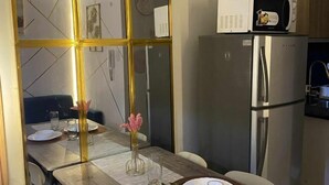 Une cuisine moderne avec un réfrigérateur en acier inoxydable, un four à micro-ondes placé sur le dessus, et une table à manger mise avec des assiettes et des verres.