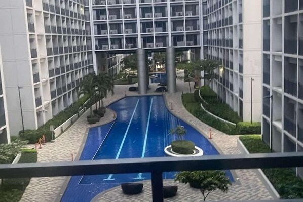 A modern building with a central blue water feature, surrounded by greenery and a paved walkway. - Shore 2 Residences Tower 3 (Pasay)