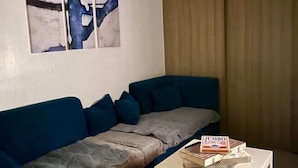 Un salon avec un canapé bleu, une table basse blanche et un tableau accroché au mur.