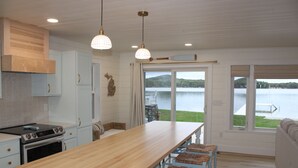 Una cocina con una isla de madera, armarios blancos y vistas a un lago.