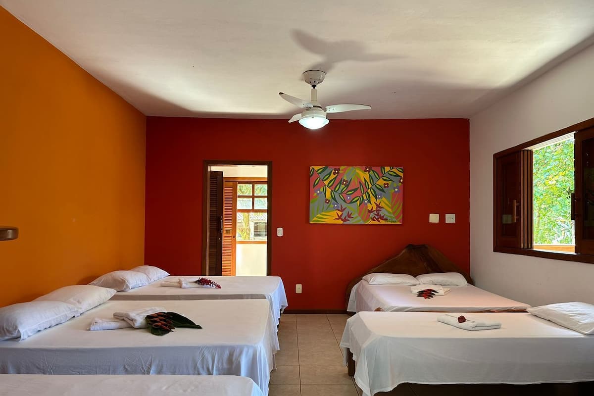 Habitación de hotel con dos camas, ventilador de techo, un cuadro y ventana con vistas.