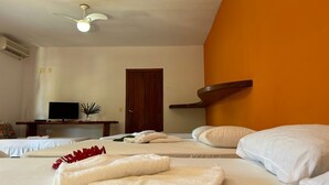 Ein Hotelzimmer mit zwei Betten, einem Fernseher, einem Deckenventilator und einer Tür.