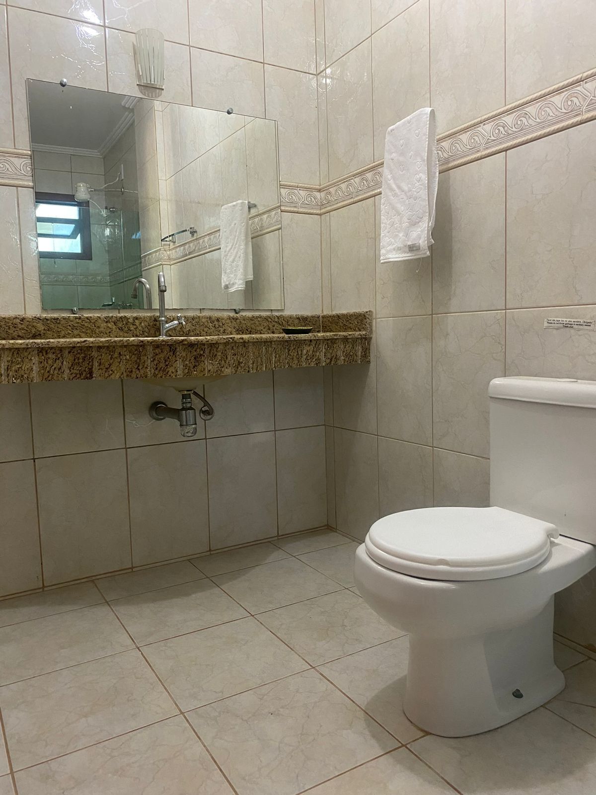 Casa de banho com sanita, lavatório com espelho e cabine de duche.