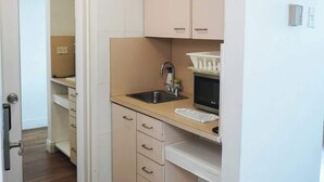 A compact kitchen with a sink, cabinets, and a microwave. - Shine Suites Studio (Miami Beach)