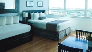 A modern bedroom with a bed, a desk, and a view of the city. - Shine Suites Studio (Miami Beach)