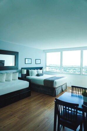 A modern bedroom with a bed, a desk, and a view of the city. - Shine Suites Studio (Miami Beach)