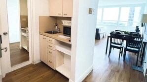 A modern kitchen with wooden cabinets, a countertop, and a dining area with chairs. - Shine Suites Studio (Miami Beach)