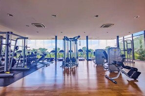 Ein Fitnessstudio mit verschiedenen Trainingsgeräten, großen Fenstern und einem Holzboden.